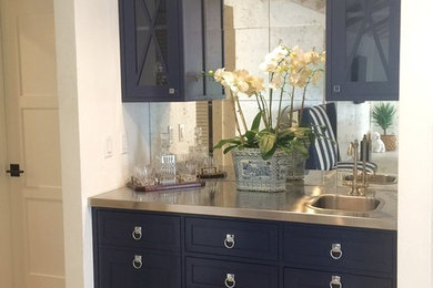 Inspiration for a coastal ceramic tile wet bar remodel in Montreal with blue cabinets, stainless steel countertops and mirror backsplash