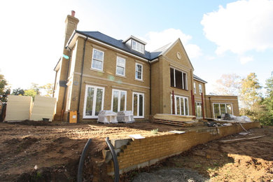Expansive and yellow traditional brick detached house in Hampshire with three floors, a pitched roof and a tiled roof.