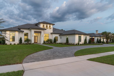 This is an example of a contemporary one-storey stucco white house exterior in Orlando with a gable roof and a tile roof.