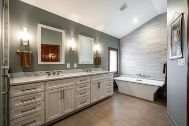 Inspiration for a large master beige tile and ceramic tile porcelain tile, beige floor, double-sink and vaulted ceiling bathroom remodel in Milwaukee with shaker cabinets, white cabinets, a one-piece toilet, green walls, an undermount sink, quartz countertops, a hinged shower door, beige countertops and a built-in vanity