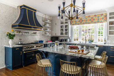 Transitional u-shaped medium tone wood floor and brown floor eat-in kitchen photo in Los Angeles with a farmhouse sink, shaker cabinets, blue cabinets, marble countertops, gray backsplash, stainless steel appliances, an island and gray countertops