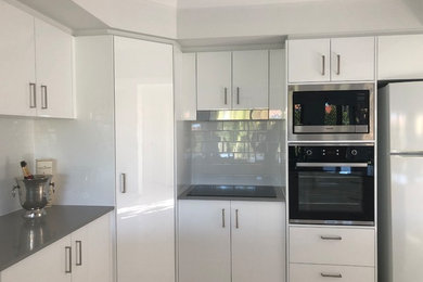 Photo of a mid-sized modern u-shaped separate kitchen in Gold Coast - Tweed with an undermount sink, white cabinets, quartz benchtops, white splashback, stainless steel appliances and grey benchtop.
