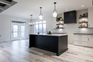 Inspiration for a mid-sized transitional l-shaped laminate floor, brown floor and coffered ceiling open concept kitchen remodel in Toronto with an undermount sink, flat-panel cabinets, white cabinets, quartz countertops, white backsplash, ceramic backsplash, stainless steel appliances, an island and white countertops