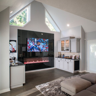 Cette image montre une grande salle de cinéma design ouverte avec un mur gris, un sol en bois brun, un téléviseur encastré et un sol marron.