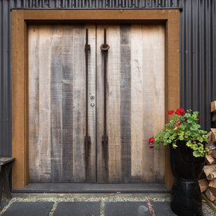 На фото: прихожая в стиле лофт с черными стенами, полом из сланца, двустворчатой входной дверью и входной дверью из дерева среднего тона с