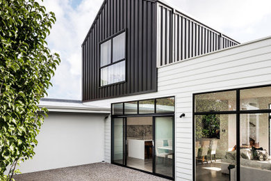 Modelo de fachada de casa blanca y negra minimalista pequeña de dos plantas con revestimiento de metal, tejado de un solo tendido, tejado de metal y panel y listón