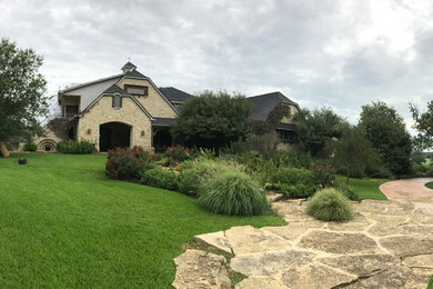 This is an example of a mid-sized traditional two-storey beige house exterior in Dallas with stone veneer, a gable roof and a shingle roof.