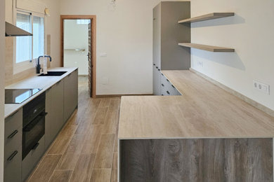 Mid-sized tuscan galley porcelain tile and brown floor eat-in kitchen photo in Alicante-Costa Blanca with an undermount sink, flat-panel cabinets, quartz countertops, beige backsplash, quartz backsplash, black appliances, a peninsula and beige countertops