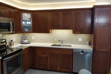 Example of a mid-sized l-shaped eat-in kitchen design in Calgary with an undermount sink, shaker cabinets, medium tone wood cabinets, quartz countertops, gray backsplash, glass tile backsplash, stainless steel appliances, no island and white countertops