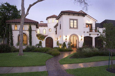 This is an example of a large mediterranean two-storey stucco white house exterior in Houston with a hip roof and a tile roof.