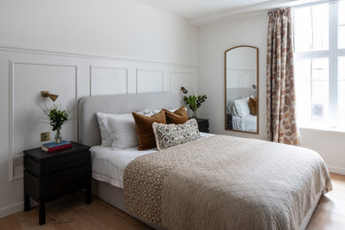 Photo of a medium sized traditional master and cream and black bedroom in London with white walls, light hardwood flooring, beige floors and panelled walls.