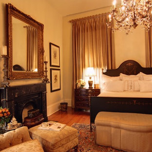 Großes Klassisches Gästezimmer mit beiger Wandfarbe, dunklem Holzboden, Kamin und verputzter Kaminumrandung in New Orleans