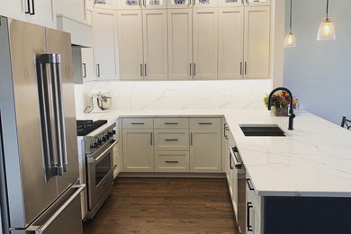 Inspiration for a mid-sized modern l-shaped dark wood floor and brown floor eat-in kitchen remodel in Chicago with an undermount sink, shaker cabinets, white cabinets, quartz countertops, white backsplash, quartz backsplash, stainless steel appliances, a peninsula and white countertops