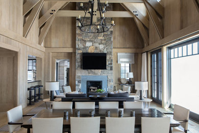 Example of a country open concept medium tone wood floor and brown floor living room design in New York with brown walls and a wall-mounted tv