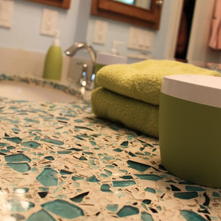 Idée de décoration pour une petite salle de bain tradition avec un lavabo encastré, un placard avec porte à panneau encastré, des portes de placard en bois brun, un plan de toilette en verre recyclé, une baignoire en alcôve, un combiné douche/baignoire, un WC séparé, un carrelage bleu, un mur bleu et un sol en carrelage de porcelaine.