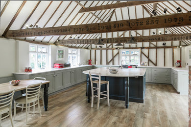 Photo of a large traditional u-shaped kitchen/diner in Other with a single-bowl sink, shaker cabinets, grey cabinets, composite countertops, integrated appliances, medium hardwood flooring and an island.