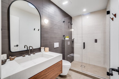 Design ideas for a modern bathroom in San Francisco with flat-panel cabinets, brown cabinets, an alcove shower, a wall-mount toilet, black and white tile, white walls, an integrated sink, concrete benchtops, a hinged shower door, white benchtops, a single vanity and a floating vanity.
