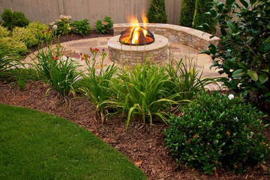 This is an example of a mid-sized contemporary full sun backyard stone landscaping in Atlanta with a fire pit.