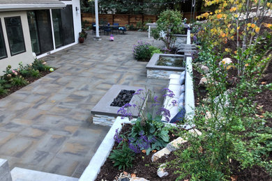 Large modern backyard patio in San Francisco with a fire feature and concrete pavers.