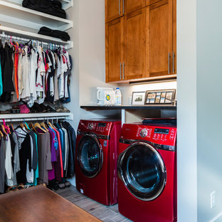Inspiration for a small traditional l-shaped laundry cupboard in Raleigh with shaker cabinets, dark wood cabinets, grey walls, light hardwood flooring, a side by side washer and dryer and grey floors.