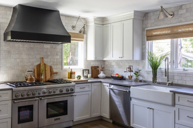 Inspiration for a mid-sized transitional u-shaped medium tone wood floor and brown floor open concept kitchen remodel in Chicago with a farmhouse sink, shaker cabinets, white cabinets, quartz countertops, white backsplash, marble backsplash, stainless steel appliances, an island and gray countertops