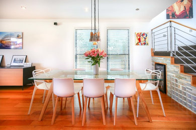 This is an example of a contemporary dining room in Sydney with white walls and medium hardwood floors.