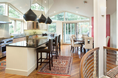 Example of a large trendy u-shaped medium tone wood floor and brown floor open concept kitchen design in Denver with an undermount sink, flat-panel cabinets, light wood cabinets, quartz countertops, blue backsplash, glass tile backsplash, stainless steel appliances, an island and black countertops