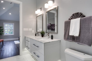 Mid-sized contemporary master bathroom in DC Metro with flat-panel cabinets, white cabinets, a two-piece toilet, white tile, grey walls, marble floors, an undermount sink, marble benchtops, white floor and grey benchtops.