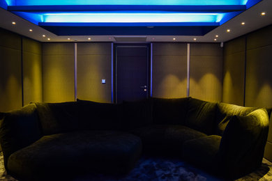 This is an example of a mid-sized modern enclosed home theatre in Surrey.