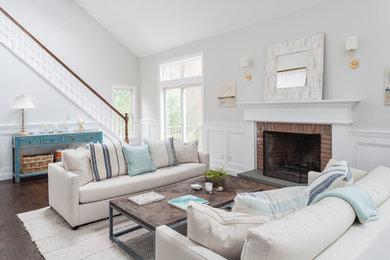 This is an example of a mid-sized beach style open concept living room in New York with grey walls, dark hardwood floors, a standard fireplace, a brick fireplace surround and no tv.