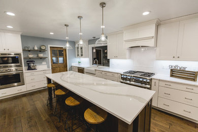 Eat-in kitchen - large country l-shaped dark wood floor and brown floor eat-in kitchen idea in Other with a farmhouse sink, shaker cabinets, white cabinets, quartz countertops, white backsplash, subway tile backsplash, stainless steel appliances and an island