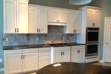 Eat-in kitchen - large transitional u-shaped eat-in kitchen idea in Indianapolis with shaker cabinets, white cabinets, granite countertops, gray backsplash, stone tile backsplash, stainless steel appliances and a peninsula