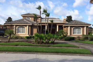 Large tropical two-storey stucco brown exterior in Tampa with a hip roof and a tile roof.