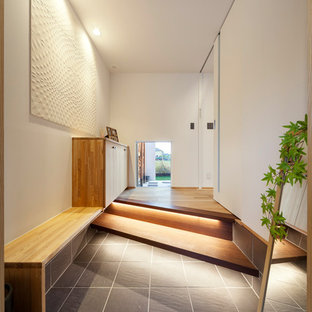 他の地域のアジアンスタイルのおしゃれな玄関ホール (白い壁、黒いドア、グレーの床) の写真