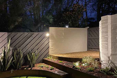 Photo of a small and australian native modern front yard partial sun xeriscape for fall in Melbourne with with raised garden bed, gravel and a wood fence.