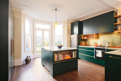 Medium sized contemporary l-shaped kitchen in London with flat-panel cabinets, green cabinets, metallic splashback, an island and white worktops.
