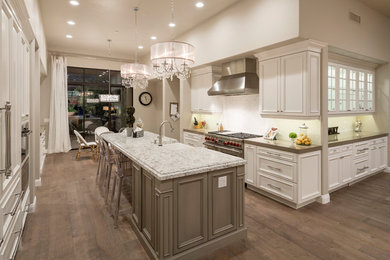 Large transitional galley medium tone wood floor and brown floor open concept kitchen photo in Phoenix with a farmhouse sink, beaded inset cabinets, white cabinets, granite countertops, stainless steel appliances and an island