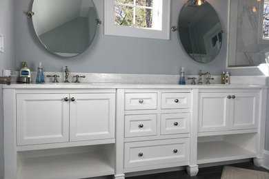 Photo of a mid-sized transitional master bathroom in New York with furniture-like cabinets, white cabinets, an alcove shower, gray tile, marble, grey walls, an undermount sink, brown floor, vinyl floors and laminate benchtops.