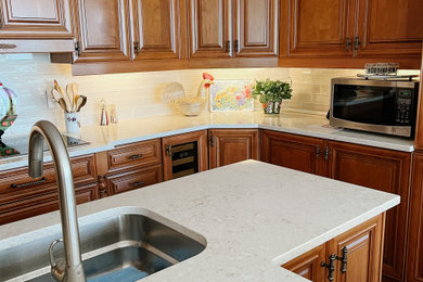Small elegant kitchen photo in Montreal with quartz countertops, white backsplash and an island