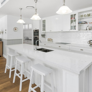 Inspiration for a large traditional galley kitchen pantry in Gold Coast - Tweed with an undermount sink, shaker cabinets, white cabinets, quartz benchtops, white splashback, subway tile splashback, stainless steel appliances, linoleum floors, with island, brown floor and yellow benchtop.