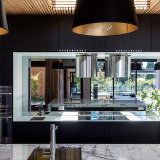 Mid-sized contemporary kitchen pantry designs - Kitchen pantry - mid-sized contemporary l-shaped kitchen pantry idea in Wollongong with an undermount sink, flat-panel cabinets, black cabinets, marble countertops, mirror backsplash, black appliances and an island