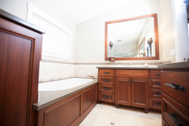 Inspiration for a small traditional master bathroom in Sacramento with recessed-panel cabinets, dark wood cabinets, an undermount tub, a corner shower, beige tile, travertine, beige walls, travertine floors, an undermount sink, solid surface benchtops, beige floor and a hinged shower door.