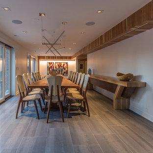This is an example of a contemporary basement with white walls, porcelain flooring, a standard fireplace, a tiled fireplace surround and grey floors.