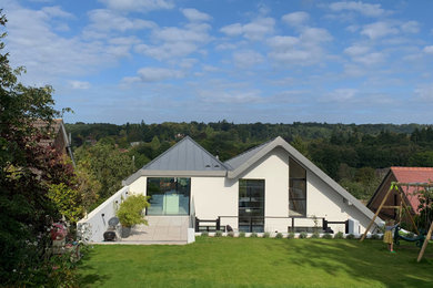 Diseño de fachada de casa blanca y gris actual grande de dos plantas con revestimiento de estuco, techo de mariposa y tejado de metal
