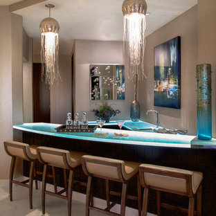 他の地域の地中海スタイルのおしゃれな着席型バー (アンダーカウンターシンク、ガラスカウンター、ベージュの床、ターコイズのキッチンカウンター) の写真