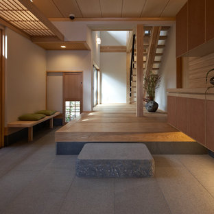 На фото: большие вестибюли в восточном стиле с белыми стенами, входной дверью из светлого дерева и серым полом