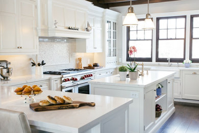 Inspiration for a large traditional u-shaped kitchen in Toronto with recessed-panel cabinets, white cabinets, marble benchtops, white splashback, ceramic splashback, stainless steel appliances, dark hardwood floors, with island, brown floor, white benchtop, a farmhouse sink and exposed beam.