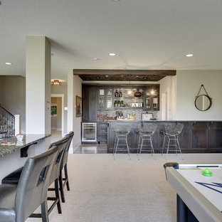 Diseño de sótano con puerta tradicional renovado, grande, con paredes grises, moqueta, chimenea tradicional, marco de chimenea de piedra y suelo gris