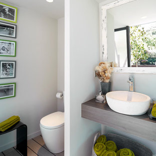 Diseño de aseo contemporáneo, de tamaño medio, con sanitario de una pieza, paredes blancas, suelo de madera clara, lavabo sobreencimera, encimera de madera y encimeras marrones