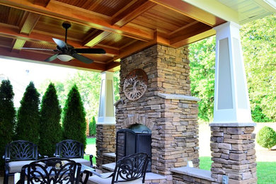 This is an example of a mid-sized rustic stamped concrete back porch design in St Louis with a fire pit and a roof extension.